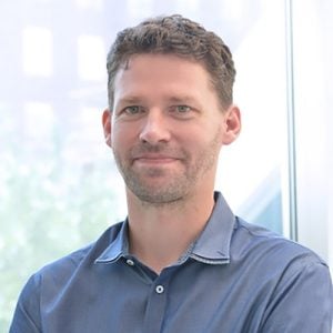 A headshot of Axel Krieger wearing a gray shirt.